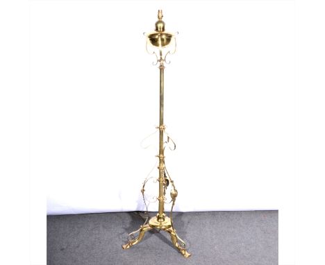 An English Art Nouveau brass standard lamp, scrolled tripod base, converted to electricity, with shade, 145cm inc. fittings.
