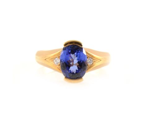 A tanzanite solitaire ring with a diamond to each shoulder, the oval mixed cut tanzanite 8.5mm x 7.2mm, bar set to top and bo