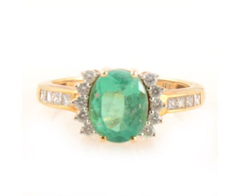 An emerald ring with diamonds to each side and to shoulders, the oval mixed cut emerald 9.2mm x 7mm, four claw set with five 