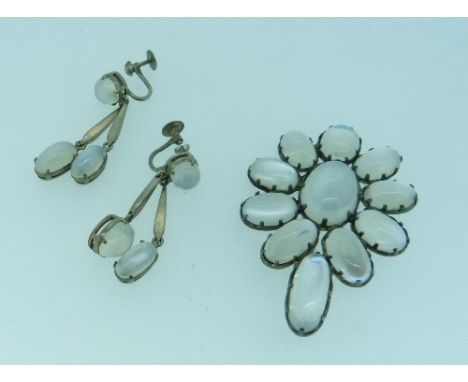 A large Moonstone Brooch, of flower-head form, the central oval stone surrounded by nine stones with an elongated stone at th