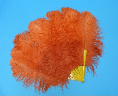 A circa 1920s flamboyantly styled orange ostrich feather Fan, with eight yellow resin sticks/guards, 24in (61cm) long,  29in 