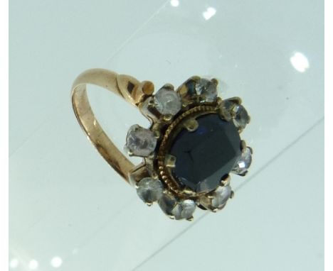 A sapphire and white sapphire Cluster Ring, the central oval stone with eight separate claw set white sapphires around, mount