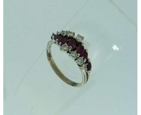 A modern ruby and diamond Dress Ring, set on the cross with seven navette shaped pale rubies, with four graduated diamond abo