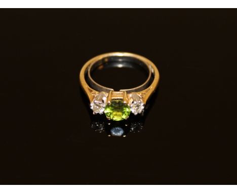 A peridot and diamond three stone ring