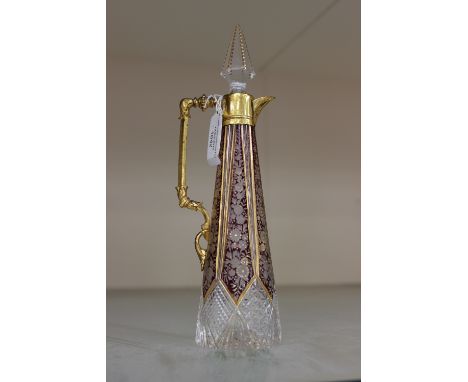 A Bohemian ruby flashed and cut ewer of tapered cylindrical outline, with French ormolu mounts, glass stopper, gilt detail th