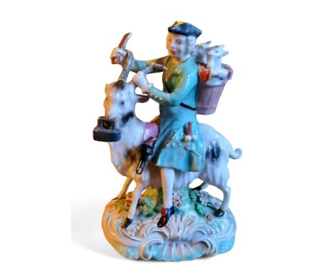 A Derby figure, The Welch Tailor,&nbsp; seated astride a goat, he wearing a tricorn hat with a pannier on his back with two k