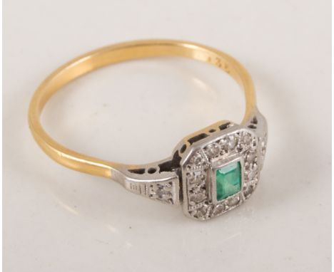 An emerald and diamond cluster ring, the rectangular step cut stone surrounded by twelve, eight cut diamonds, in a yellow and