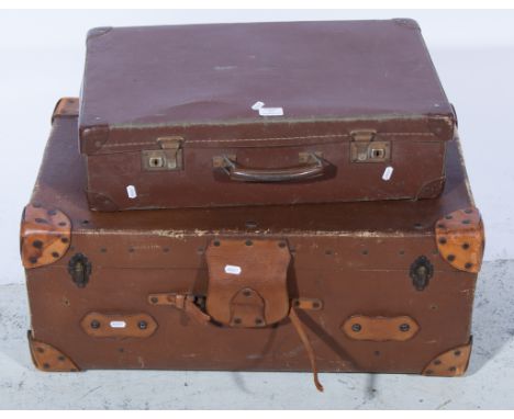 An old travelling trunk with leather corner mounts, handles and straps together with a fibreboard suitcase. (2)