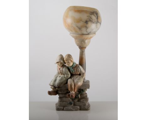 Dutch Art Nouveau style pottery and alabaster tablelamp, modelled with two children sitting on a wall, under a street light, 