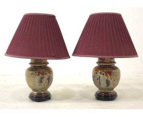 A pair of 20th century Japanese ceramic table lamps, decorated with figure against a buff ground, on wooden bases and with da