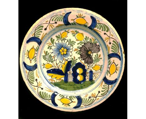 tAn 18thC Dutch Delftware plate, decorated in polychrome colours with large peony type flowers and rockwork within a border o
