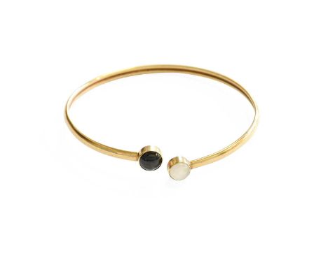 A 9 Carat Gold Torque Bangle, set with moonstone and a black stone cabochon, inner measurements 6.6cm by 6.4cm approximatelyG