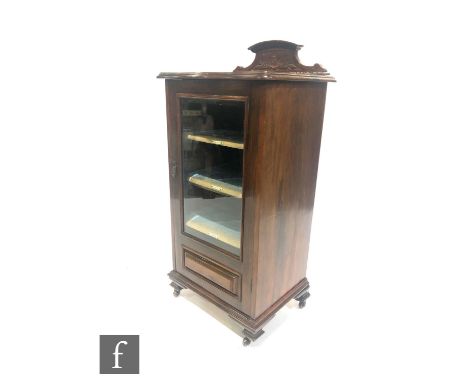 An Edwardian mahogany serpentine fronted music cabinet, the fitted shelf interior enclosed by a glazed door below a carved sh