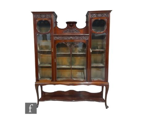 An Edwardian triple door mahogany display cabinet enclosed by glazed doors with carved panelled front and central fan bar doo