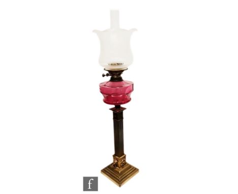An Edwardian brass oil lamp, ruby shade on stepped lion mask base, height 72cm. 
