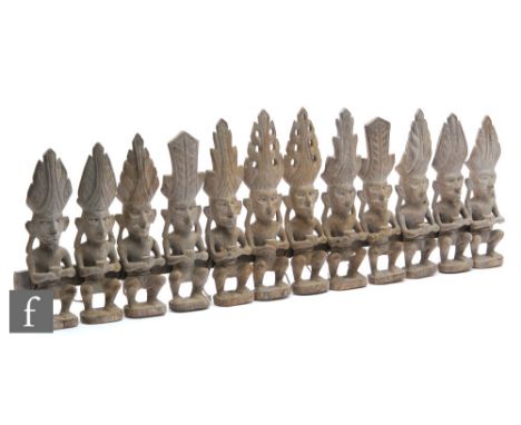 A carved wooden Borneo, Sarawak ancestor or spirit carving, the group comprising twelve individual carved seated figures hold