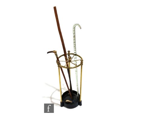 A Victorian circular brass stick stand with six divisions, three supports to a cast iron base, centre finial, height 57cm, wi