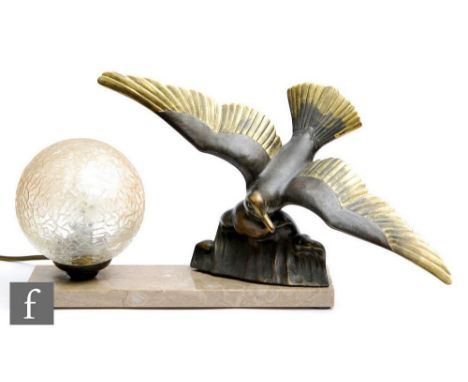 An Art Deco table lamp modelled as a bronzed spelter seagull in flight above a crashing wave with gilt details, with a crackl