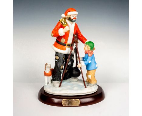 Hand painted porcelain figure of a clown Santa and a child with a tripod cooking pot. Sits on a wooden base with gold-tone ti