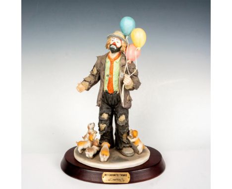 Hand painted porcelain figure if a clown with balloons and puppies. Sits on a wooden base with gold-tone titled plaque. Emmet