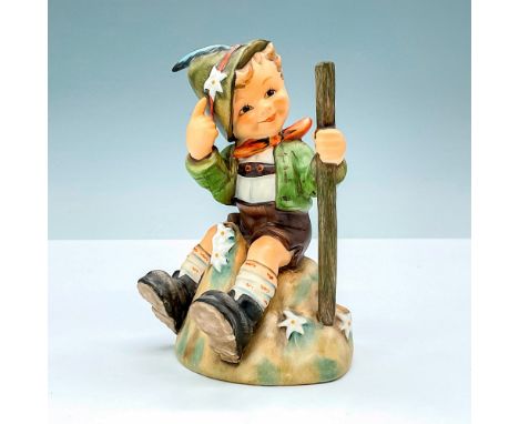 M.I. Hummel hiker figurine resting amid Edelweiss on a mountaintop. With a blossom in his hat for luck and a walking stick in