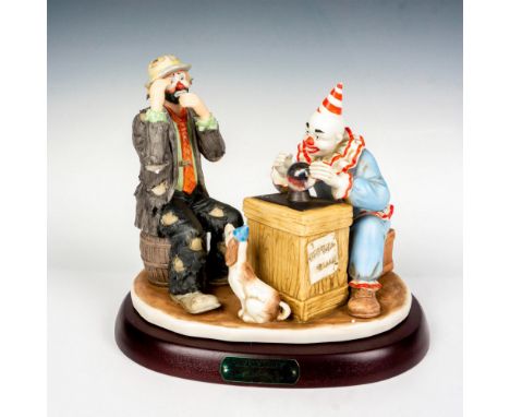 Hand painted porcelain figure of a fortune teller clown over a crystal ball. Sits on a wooden base with gold-tone titled plaq