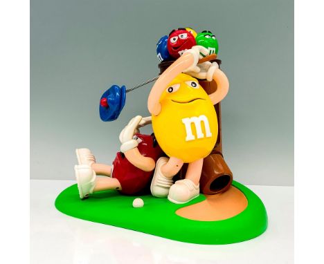 A plastic candy dispenser that depicts the yellow and red m and m playing golf on a field together with caddy being used for 