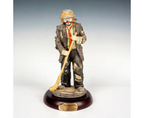 Hand painted porcelain figure of a clown sweeping. Sits on a wooden base with gold-tone titled plaque. Emmett Kelly Jr. backs