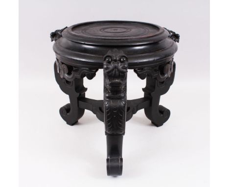 A CHINESE 19TH / 20TH CENTURY EBONISED HARDWOOD PLANT / VASE STAND, the three feet carved with mythical dragon / lion dog hea