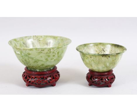 A GOOD PAIR OF 20TH CENTURY CHINESE GREEN JADE / HARDSTONE BOWLS, with accompanying carved stands, 13cm &amp; 10cm.