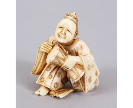 A GOOD JAPANESE MEIJI PERIOD CARVED IVORY NETSUKE OF SAIZO MUSICIAN, the musician in a crouched position whilst holding a dru