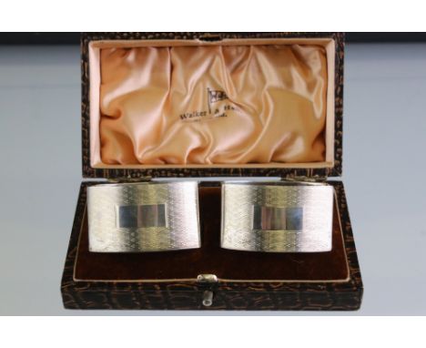 Boxed pair of Walker &amp; Hall silver napkin rings with engine turned decoration and vacant cartouches, Sheffield 1934, each