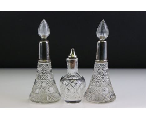 Pair of George V silver collared conical cut glass scent bottles with star-cut bases, with flame-form stoppers, London 1920, 