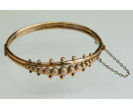 Late 19th century 9ct rose gold hinged bangle, fifteen graduated scroll textured spheres to the centre, granulation detailing