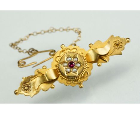 Edwardian ruby and seed pearl 9ct gold bar brooch, the central raised circular panel with flower head design, small round mix
