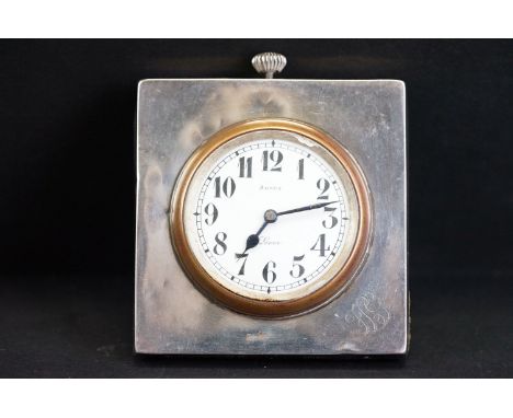 Eight day silver cased travel clock, white enamel dial, black Arabic numerals and poker hands, initialled silver surround, le