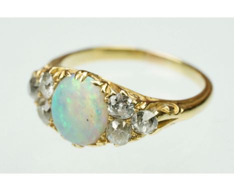 Opal and diamond unmarked yellow gold ring, the central oval cabochon cut precious white opal displaying indigo, blue, green,