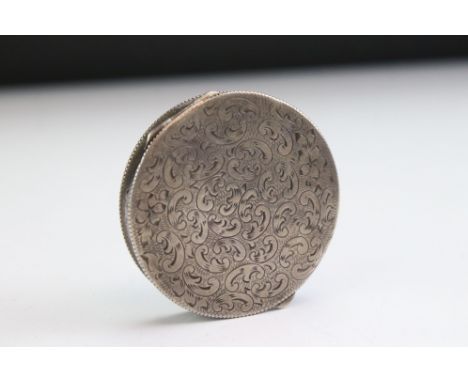 Continental silver pill box of circular form, with engraved scrolling &amp; floral decoration to the hinged lid, mirror to th
