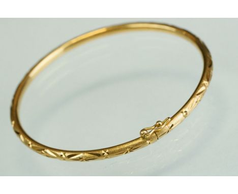 Unmarked yellow gold bangle, bright cut star decoration, tongue and tube clasp with safety catch, width approx 2.9mm, interio