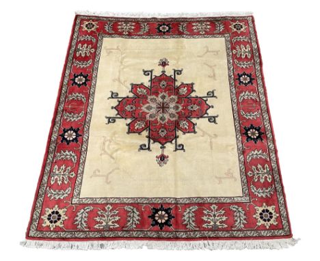 Persian Heriz rug, the ivory ground field with large floral central medallion and pale linear decoration, red ground guarded 