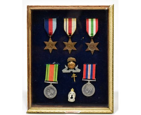 A framed panel of medals and cap badges comprising 1939-45 Star, The Africa Star, The Italy Star, 1939-45 Star and a Defence 