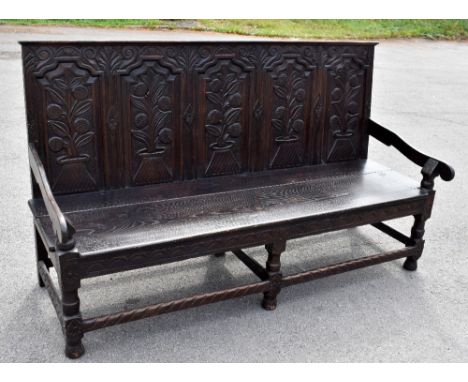A Victorian carved oak settle in 18th century style, with five panel back above a solid seat on turned and block legs, height