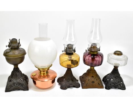 Four early 20th century oil lamps including an example with aubergine coloured glass reservoir, height including chimney 46cm