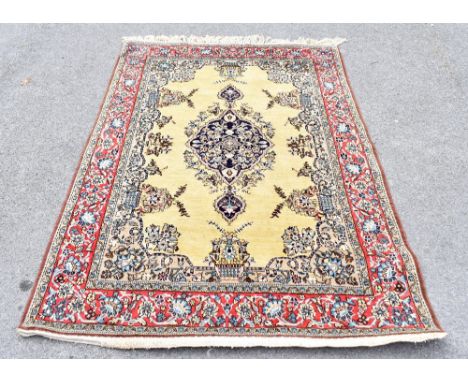 A Persian hand woven wool carpet, decorated with a central medallion against a pale green ground, 202 x 139cm.