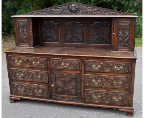 A 19th century carved oak Flemish style sideboard, the back section with carved lion mask, flanked by mythical creatures, abo