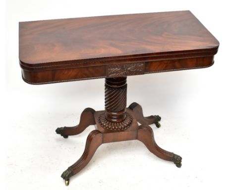 An early 19th century mahogany fold over swivel-top tea table with carved detail to the front, on a wrythen column support te