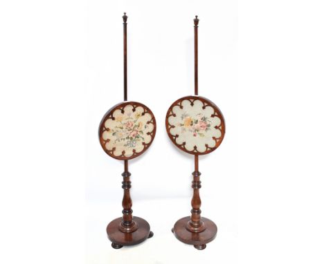 A pair of William IV rosewood pole screens, each circular screen inset with a floral tapestry panel, with turned column and c