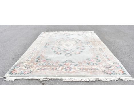 A large Chinese wool carpet decorated with a central floral medallion against a pale green ground, size 366 x 272cm