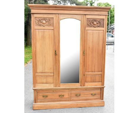 A walnut twin door wardrobe with moulded cornice above the central mirrored plate flanked by a pair carved and panelled doors