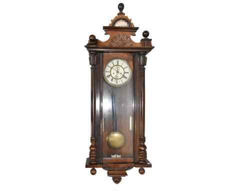 An early 20th century stained beech Vienna style wall clock, the carved pediment with circular dial set with Roman numerals, 